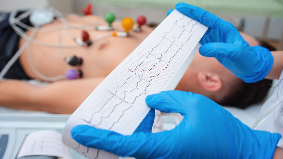 Medical professional reviewing an ECG printout near a patient.