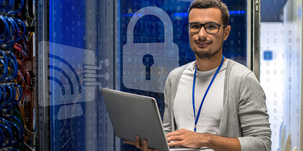 Tech professional holding a laptop with digital security icons in the background.