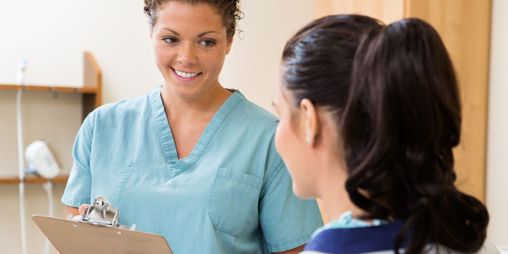 A nurse smiling and talking to a patient.
